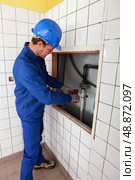 Plumber working in a tiled room. Стоковое фото, агентство Ingram Publishing / Фотобанк Лори