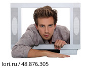 Young man trying to climb out of a tv set. Стоковое фото, агентство Ingram Publishing / Фотобанк Лори