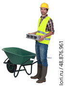 Man placing brick into wheelbarrow. Стоковое фото, агентство Ingram Publishing / Фотобанк Лори