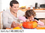 Father carving pumpkins with his daughter. Стоковое фото, агентство Ingram Publishing / Фотобанк Лори