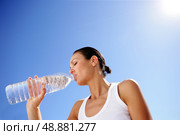 Woman drinking a bottle of water against a blue sky. Стоковое фото, агентство Ingram Publishing / Фотобанк Лори