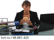 Woman eating a hamburger at her desk. Стоковое фото, агентство Ingram Publishing / Фотобанк Лори