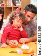 Parents helping child with Halloween decorations. Стоковое фото, агентство Ingram Publishing / Фотобанк Лори