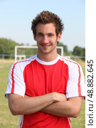 Grinning footballer with goal in the background. Стоковое фото, агентство Ingram Publishing / Фотобанк Лори