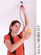 Woman using a voltmeter on ceiling electrics. Стоковое фото, агентство Ingram Publishing / Фотобанк Лори
