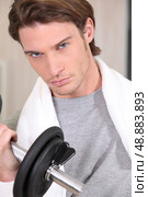 Portrait of a determined man lifting a dumbbell. Стоковое фото, агентство Ingram Publishing / Фотобанк Лори