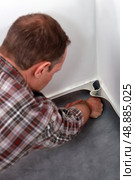 Man pushing linoleum into the corner of a room. Стоковое фото, агентство Ingram Publishing / Фотобанк Лори