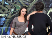 Couple hanging out by a wall painted with graffiti. Стоковое фото, агентство Ingram Publishing / Фотобанк Лори
