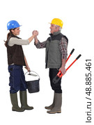 Male and female manual workers shaking hands. Стоковое фото, агентство Ingram Publishing / Фотобанк Лори