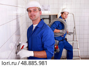 two skilled tradesman in blue jumpsuites working in a empty room. Стоковое фото, агентство Ingram Publishing / Фотобанк Лори