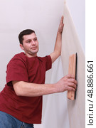 Decorator smoothing down wallpaper with a brush. Стоковое фото, агентство Ingram Publishing / Фотобанк Лори