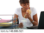 Office worker having a quick lunch in front of her computer. Стоковое фото, агентство Ingram Publishing / Фотобанк Лори