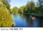 People ride water bikes or pedal catamarans on a pond in a city park on a sunny spring day. Active outdoor recreation. Saint Petersburg, city park on Elagin Island. Picturesque spring landscape. Стоковое фото, фотограф Виктория Катьянова / Фотобанк Лори