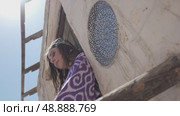 A young woman with long hair in an oriental robe and skullcap stands in the wind near an ancient mosque. Стоковое видео, видеограф Aleksey Kidisyuk / Фотобанк Лори
