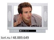 young man through a TV screen listening something carefully. Стоковое фото, агентство Ingram Publishing / Фотобанк Лори