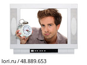Man holding alarm clock trapped in the television. Стоковое фото, агентство Ingram Publishing / Фотобанк Лори