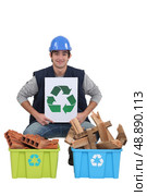 craftsman holding a recycling label over two boxes of used materials. Стоковое фото, агентство Ingram Publishing / Фотобанк Лори