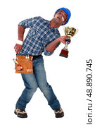 Accident prone construction worker holding a trophy. Стоковое фото, агентство Ingram Publishing / Фотобанк Лори