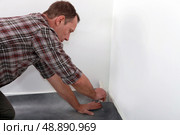 Man fitting linoleum flooring into the corner of a room. Стоковое фото, агентство Ingram Publishing / Фотобанк Лори