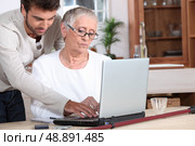 Young man helping a senior with a laptop computer. Стоковое фото, агентство Ingram Publishing / Фотобанк Лори