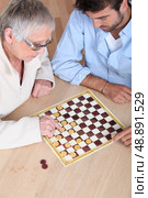Mother and son playing drafts. Стоковое фото, агентство Ingram Publishing / Фотобанк Лори