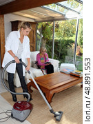 Girl vacuuming for an elderly woman. Стоковое фото, агентство Ingram Publishing / Фотобанк Лори