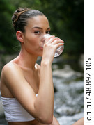 Woman drinking water by a brook. Стоковое фото, агентство Ingram Publishing / Фотобанк Лори