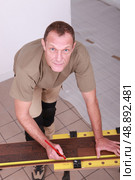 Man at home cutting wooden flooring to size. Стоковое фото, агентство Ingram Publishing / Фотобанк Лори