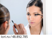 Brunette applying eye make-up. Стоковое фото, агентство Ingram Publishing / Фотобанк Лори