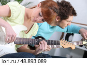 Young couple tuning and playing guitar. Стоковое фото, агентство Ingram Publishing / Фотобанк Лори