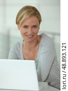 Casual woman using a white laptop computer in a white room. Стоковое фото, агентство Ingram Publishing / Фотобанк Лори