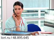 young nurse at phone behind her computer. Стоковое фото, агентство Ingram Publishing / Фотобанк Лори