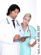 Doctor going over a patient’s record with his assistant. Стоковое фото, агентство Ingram Publishing / Фотобанк Лори