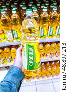 Масло подсолнечное «Слобода» в руке в супермаркете. Различные бутилированные подсолнечные масла. Редакционное фото, фотограф FotograFF / Фотобанк Лори