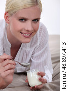 Woman eating yogurt in bed. Стоковое фото, агентство Ingram Publishing / Фотобанк Лори