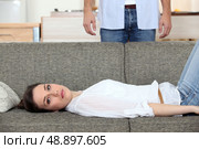 Woman laying on couch husband stood behind. Стоковое фото, агентство Ingram Publishing / Фотобанк Лори