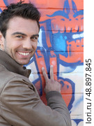 V for Victory from a man in front of grafitti. Стоковое фото, агентство Ingram Publishing / Фотобанк Лори