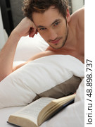 Young man reading a book in bed. Стоковое фото, агентство Ingram Publishing / Фотобанк Лори
