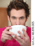 Young man drinking out of a bowl. Стоковое фото, агентство Ingram Publishing / Фотобанк Лори