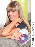 blonde teenager behind a couch and holding cd cases. Стоковое фото, агентство Ingram Publishing / Фотобанк Лори