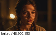 Young woman with braids looking contemplative in dim candlelight. Стоковое AI-видео, аниматор KATERINA AI / Фотобанк Лори