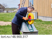 Conducting wheel fitting on hand cart, DIYer mounts polyurethane foam wheel to achieve long lasting operation and minimize risk of unexpected repairs. Стоковое фото, фотограф Владимир Григорьев / Фотобанк Лори