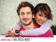 Young couple watching TV with a remote control. Стоковое фото, агентство Ingram Publishing / Фотобанк Лори