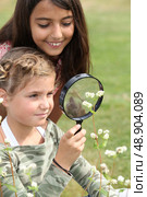 Girls looking through magnifying glass. Стоковое фото, агентство Ingram Publishing / Фотобанк Лори