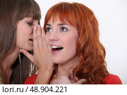 Woman whispering into another woman’s ear. Стоковое фото, агентство Ingram Publishing / Фотобанк Лори