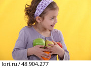 A little girl with her arms full of fruits. Стоковое фото, агентство Ingram Publishing / Фотобанк Лори
