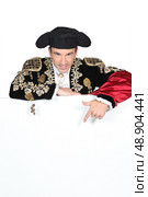 Man in a matador costume with a board blank for text or image. Стоковое фото, агентство Ingram Publishing / Фотобанк Лори