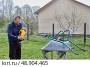 Removing packaging from new tire and getting ready to install wheel on garden wheelbarrow for maintenance and improved functionality outdoors. Стоковое фото, фотограф Владимир Григорьев / Фотобанк Лори