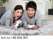 Couple playing a video game together. Стоковое фото, агентство Ingram Publishing / Фотобанк Лори