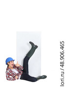 Playful woman lying in front of a blank sign and giving the thumb’s up. Стоковое фото, агентство Ingram Publishing / Фотобанк Лори